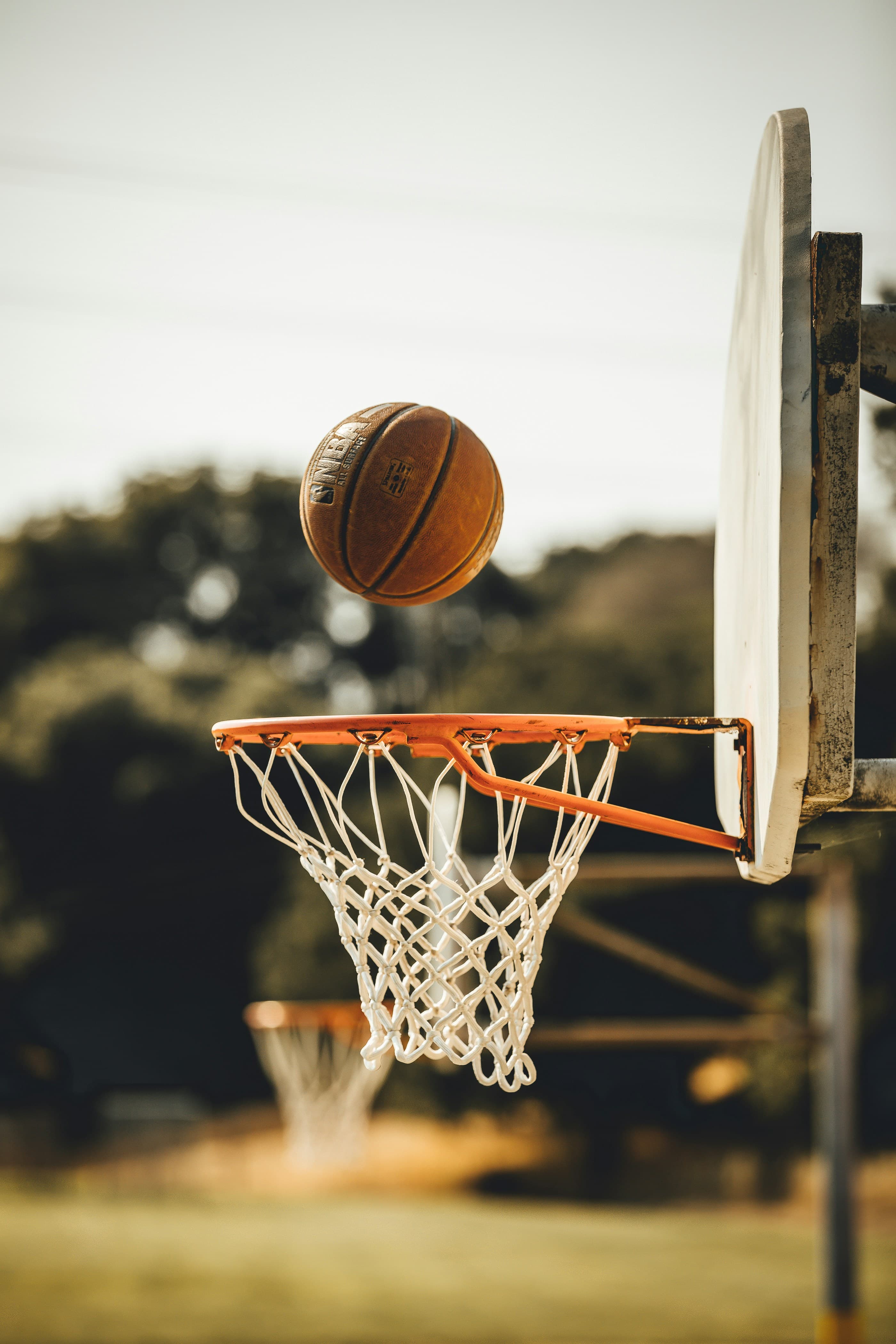 A basketball dropping through the hoop. Photo by Tom Briskey on Unsplash