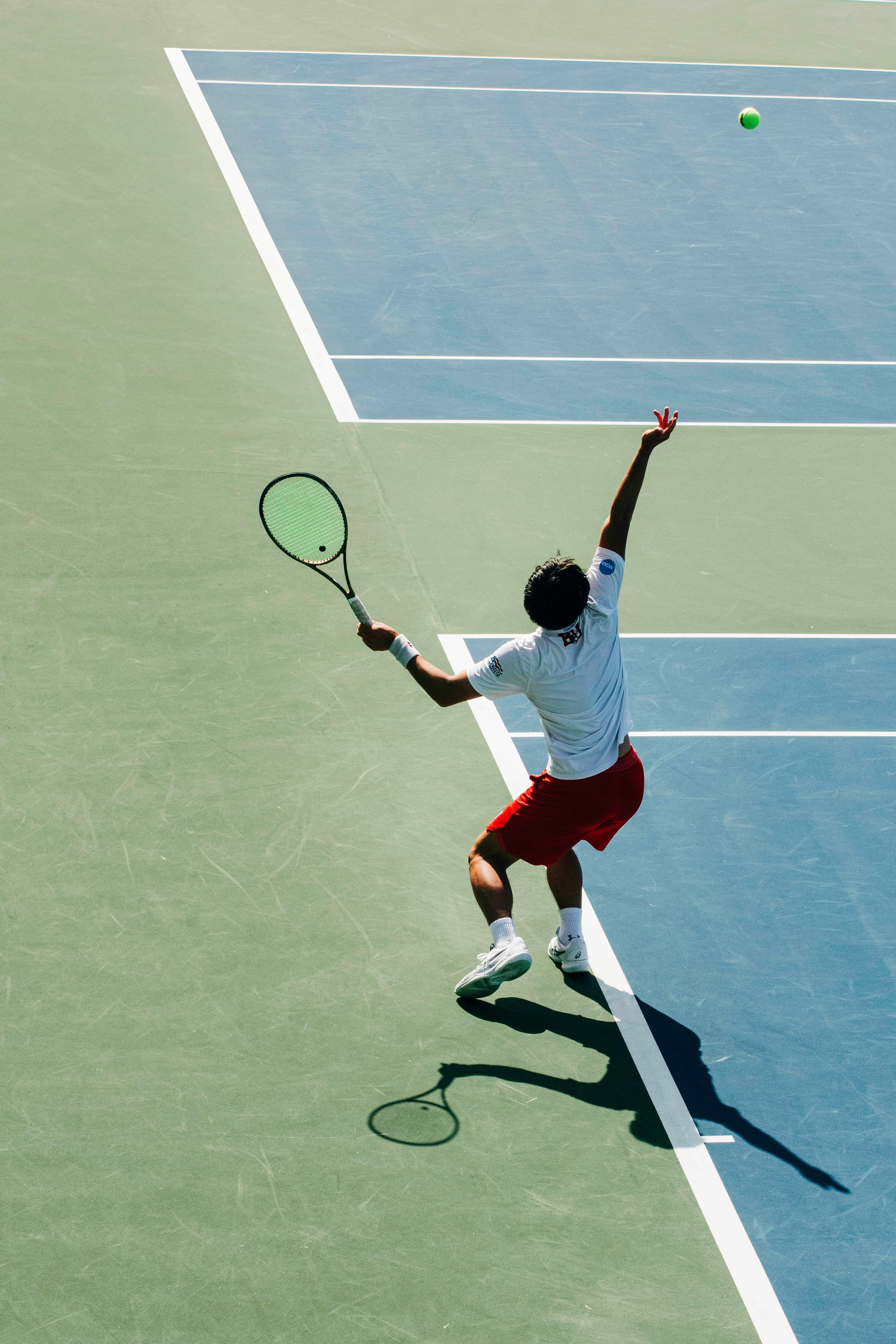 A man swinging a tennis racquet on a tennis court. Photo by Andrew Heald on Unsplash
