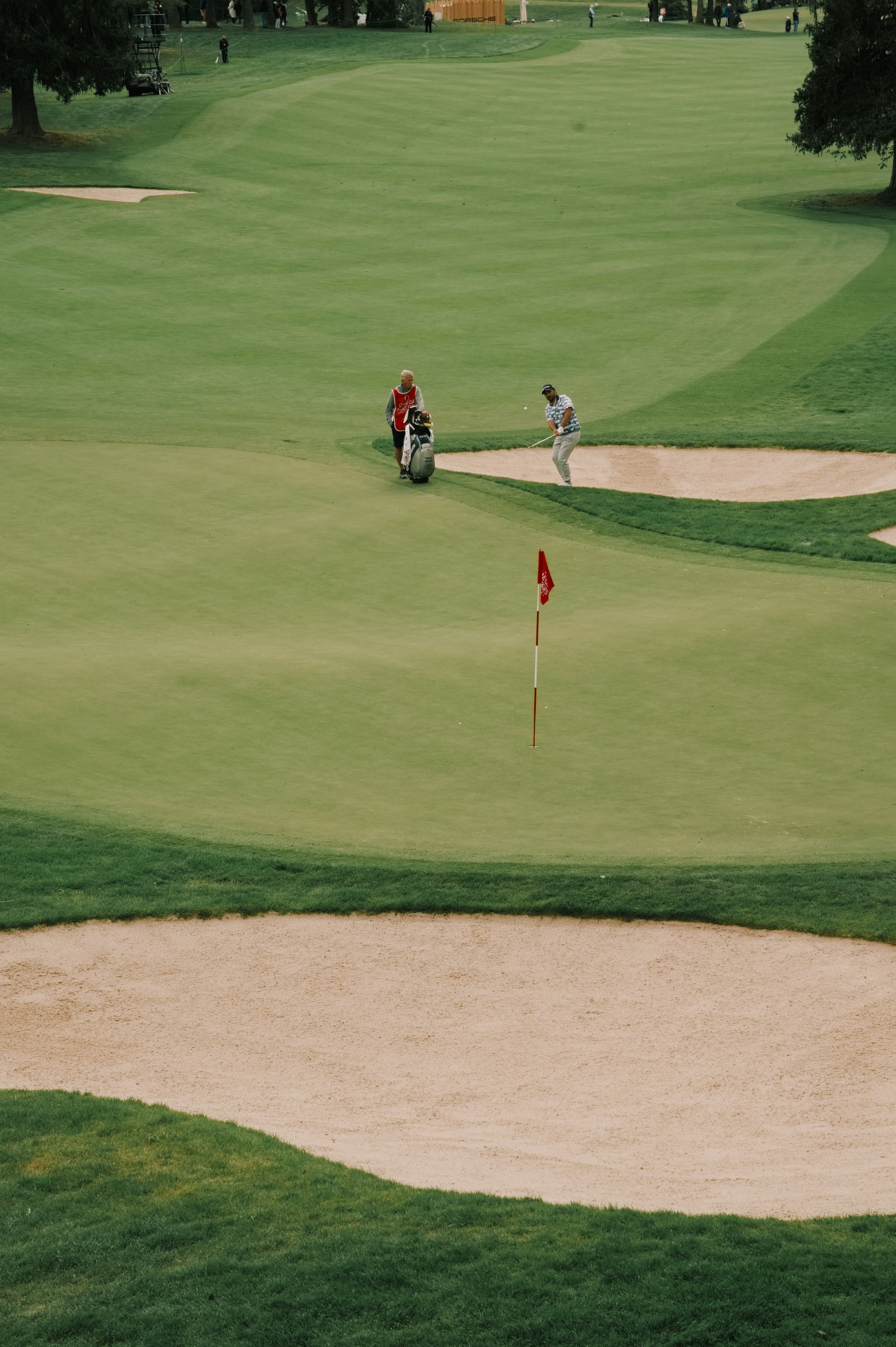 A golfer on a green with sand traps and a flag. Photo by Felix Vericel on Unsplash
