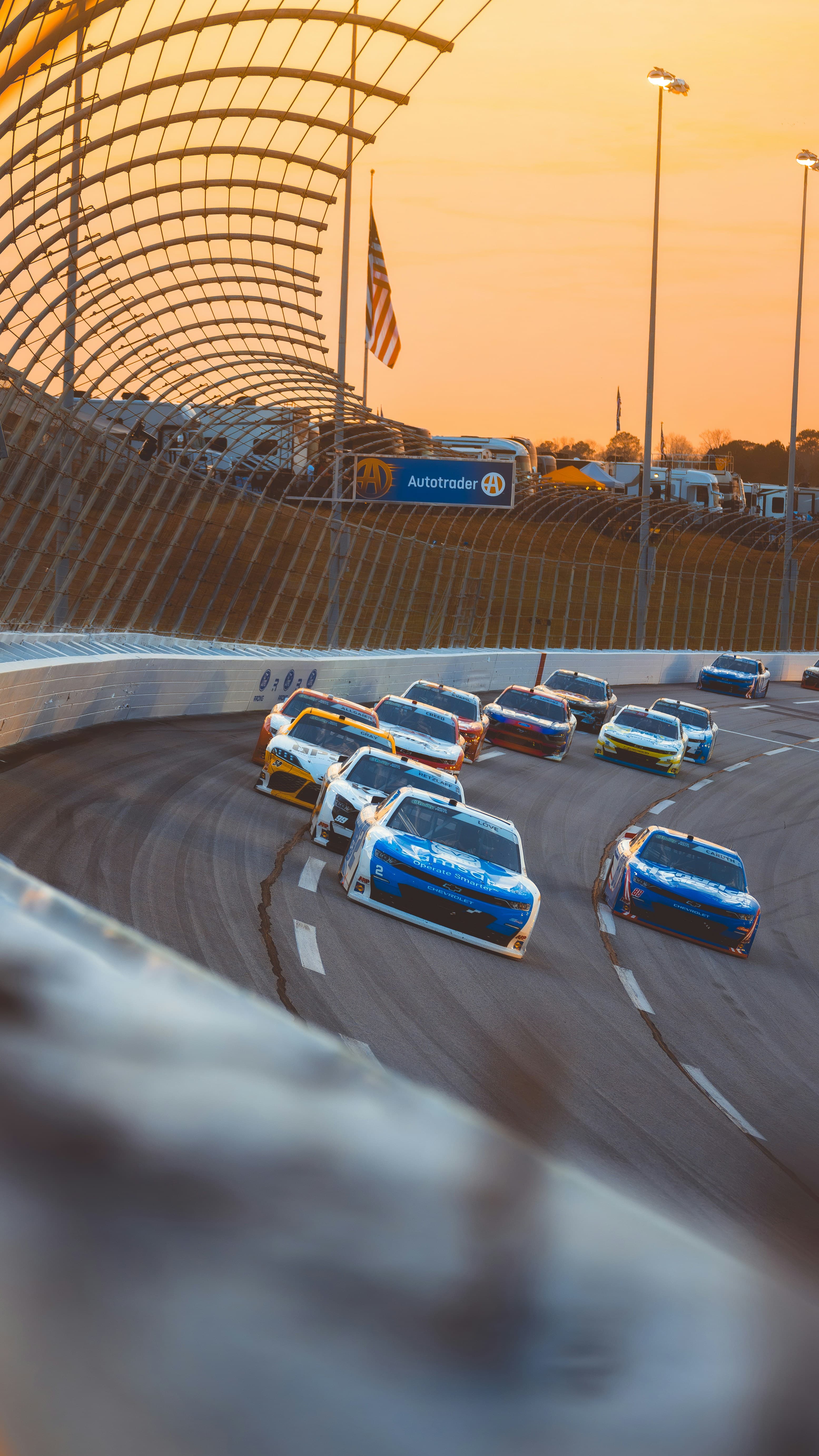 Race cars speeding around a track at sunset. Photo by Casey Calhoun on Unsplash
